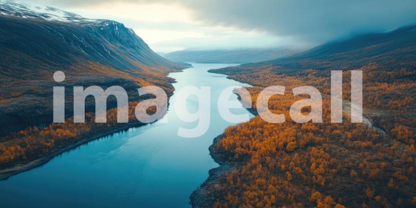 Aerial View of a Serpentine River Flowing Through a Valley of Autumnal Trees, with Snow-capped Mountains in the Distance