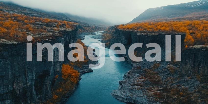 Aerial View of a Serpentine River Flowing Through a Valley of Autumnal Trees, with Snow-capped Mountains in the Distance