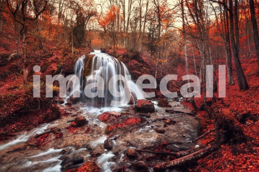 Beautiful waterfall with trees, red leaves, rocks and stones in